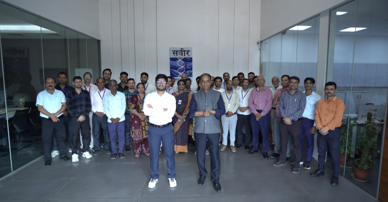 Saveer team gathered together at the company office beneath the Saveer logo